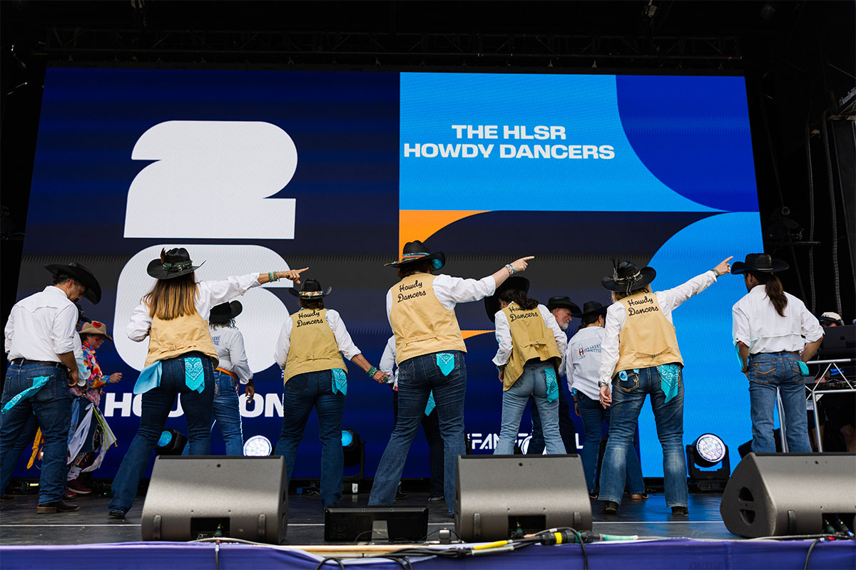 The HLSR Howdy Dancers perform on stage at the FIFA Fan Fest in Houston. The group, dressed in white shirts, tan vests embroidered with